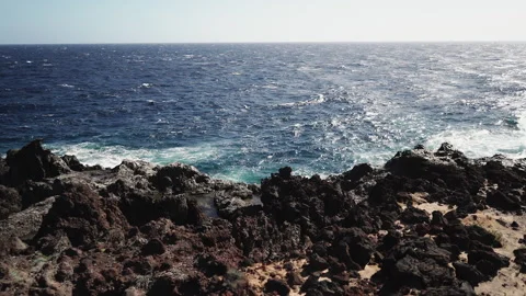 The waves of the ocean crash against the rocks and stones of the coast. Stock Footage 145277357
