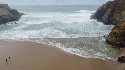 Waves of the ocean. Drone shot. People walking on the beach. Video stock 143496038