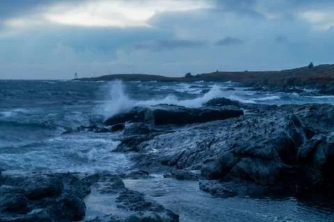 Waves from ocean hitting rocks with clouds Stock Photos