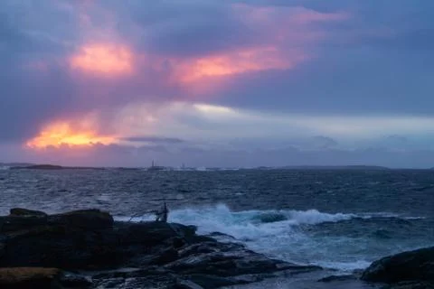 Waves from ocean hitting rocks with clouds an sunset Stock Photos