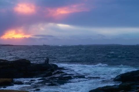 Waves from ocean hitting rocks with clouds an sunset Stock Photos