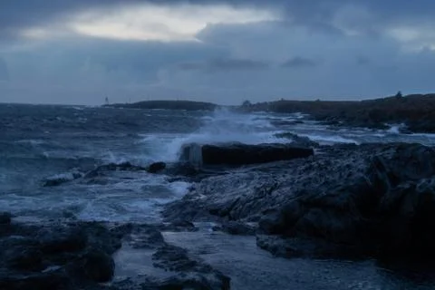 Waves from ocean hitting rocks with clouds Stock Photos