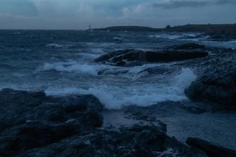 Waves from ocean hitting rocks with clouds Stock Photos
