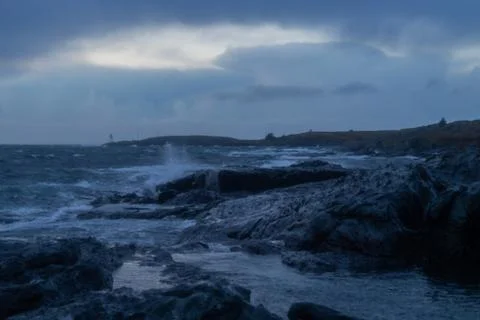 Waves from ocean hitting rocks with clouds Stock Photos