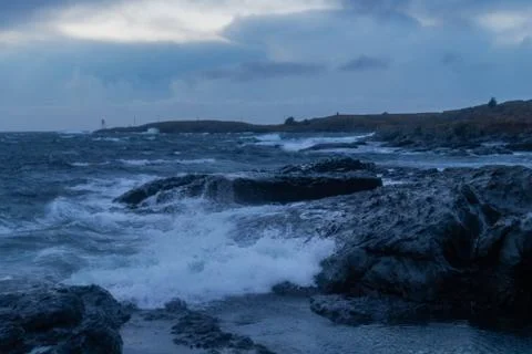 Waves from ocean hitting rocks with clouds Stock Photos