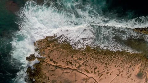 Waves of ocean roll on stone shore Blue water ocean winter Shooting from drone Stock Footage 233064922