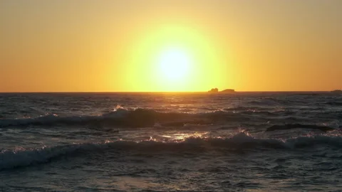 Waves on ocean at sunset with sun on horizon Stock Footage 131887548