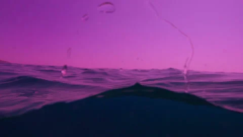 Waves on the ocean. Violet sunset. The camera goes under water. Stock-Footage 98007701