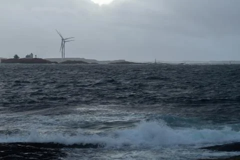 Waves from ocean with windmill in background Stock Photos