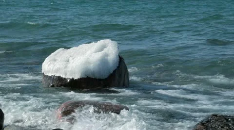 Waves over Ice Capped Boulder HD Stock Footage 10824628