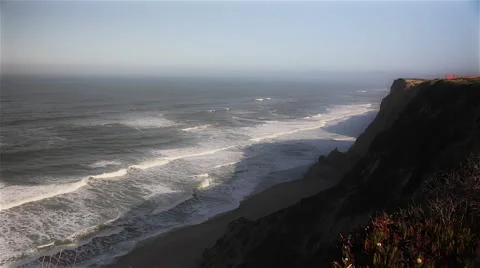 Waves of the Pacific Ocean crash on a beach at the bottom of cliffs on Highway 1 Stock Footage 46940025