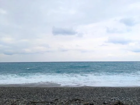 Waves from the Pacific Ocean rolling onto a pebble shore on a cloudy day in Foto stock