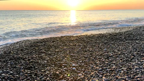 Waves at pebble stone beach on sunrise. Sunrise on shoreline. Beach pebbles. Stock Footage 317345121