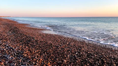 Waves at pebble stone beach on sunrise. Sunrise on shoreline. Beach pebbles. Stock Footage 317345384