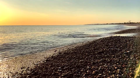 Waves at pebble stone beach on sunrise. Sunrise on shoreline. Beach pebbles. Stock Footage 317368077