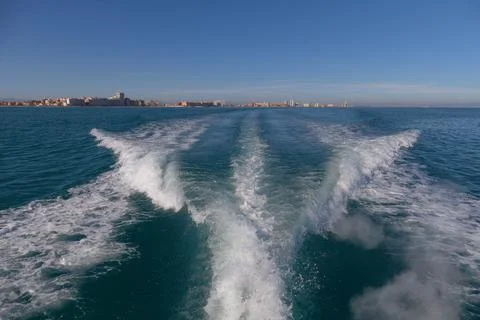 Waves produced by a ship sailing through the ocean at high speed. Water trail Stock Photos
