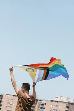 Waves a progress pride flag above his head Stock Photos