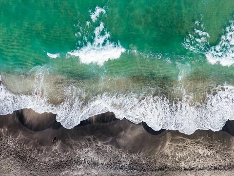Waves push onto the shore in this beach scene. The water is blue and clear. T Stock Photos