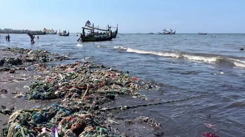 Waves pushing floating trash to a tropical beach in Eastern Java, sunny Stock Footage 249721415