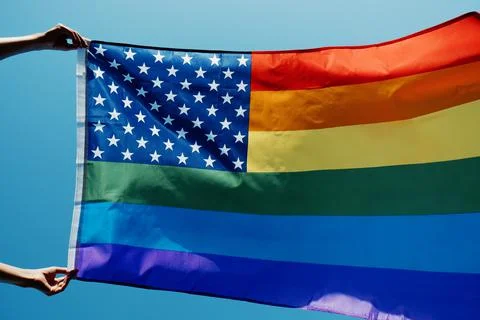 Waves a rainbow US flag on the sky Foto stock