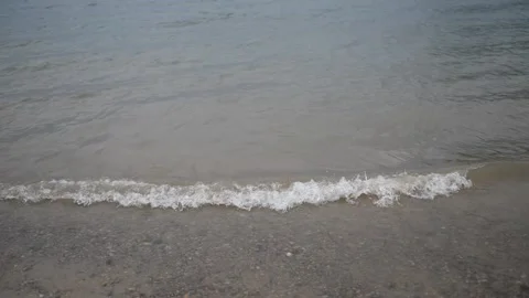 The waves of the river adjacent to the sandy shore on which many small stones Stock Footage 130871343