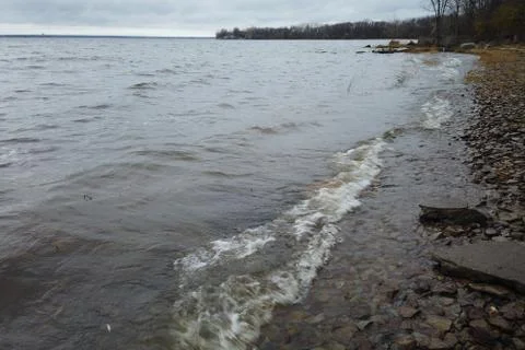 Waves of a river on the shore line Stock Photos