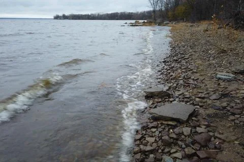 Waves of a river on the shore line Stock Photos