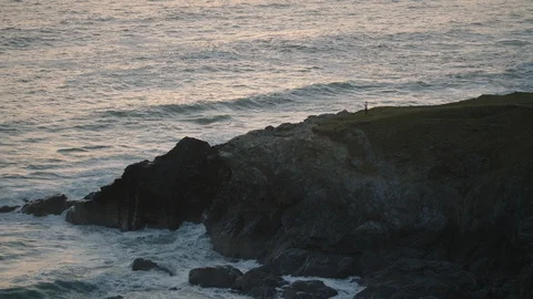 Waves roll in and break along cliff at sunset in Cornwall, England. Stock Footage 128176962
