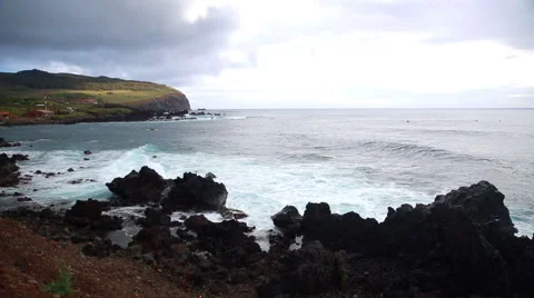 Waves roll into and crash onto the volcanic rocks on the shore Stock Footage 64257903