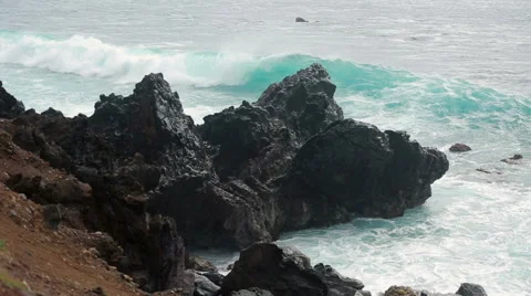 Waves roll and crash onto the volcanic rocks, seascape Stock Footage 64257916