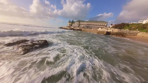 Waves roll onto beach as sun sets over rocky coastline Video stock 344551218
