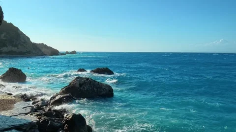 Waves roll in, breaking on dark rocks and white sand. Milos Beach Greece Stockbeeldmateriaal 344095632