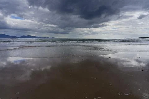 Waves roll up Llanddwyn beach, Anglesey, under dark threatening clouds. Stockfoto's