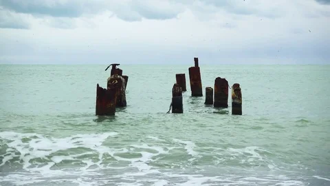 The waves roll on the pebble beach in the water the old pier Stock Footage 82170332