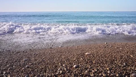 Waves roll onto a rocky beach in daylight with blue skies above and the sou.. Stock Footage 340192159
