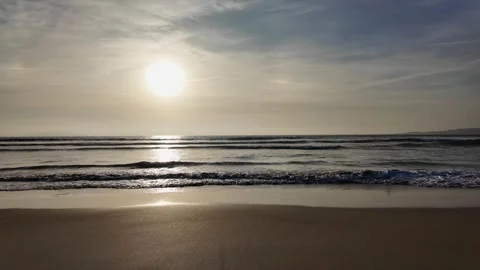 Waves roll onto a sandy beach against a background of blue sky, dramatic th.. Stock Footage 263708280