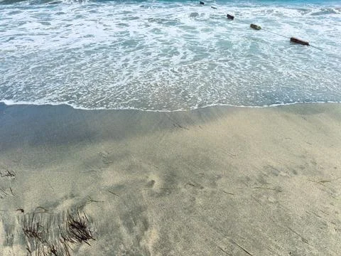 Waves roll onto the sandy beach in a coastal area. The water meets the shore  Stock Photos