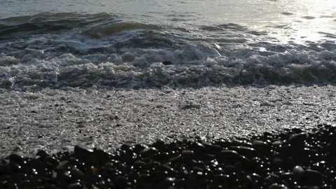 Waves roll onto the shore of the sea or ocean at sunset. Slow motion. Stock Footage 114901063