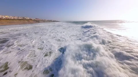 Waves roll towards shore with coastal town in view; Ericeira 库存影片 346369963