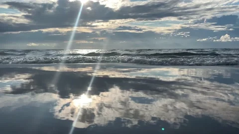 Waves roll on wet sand in which clouds are reflected as in mirror in wet surface Stock Footage 161752512