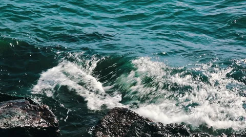 Waves rolling in and breaking on boulders Stock Footage 55903748