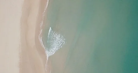 Waves rolling in and foaming on the shore of a sandy beach, aerial Stock Footage 111776243
