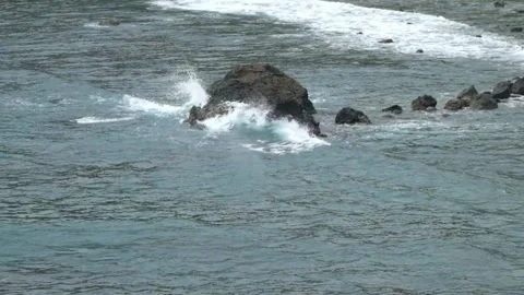 Waves rolling crashing against the rocks on the beach Stock Footage 319824294