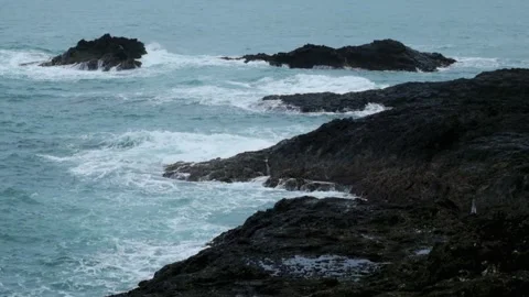 Waves rolling crashing against the rocks on the beach Stock Footage 319824444