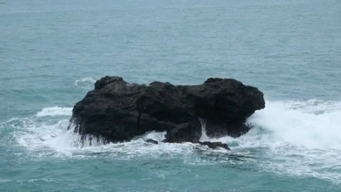 Waves rolling crashing against the rocks on the beach 4 Stock Footage 319824670