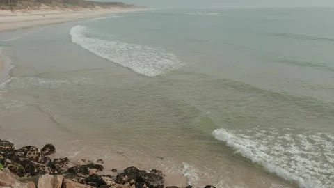 Waves Rolling onto an Empty Sandy Beach and Rocks in Portugal Stock Footage 344013391
