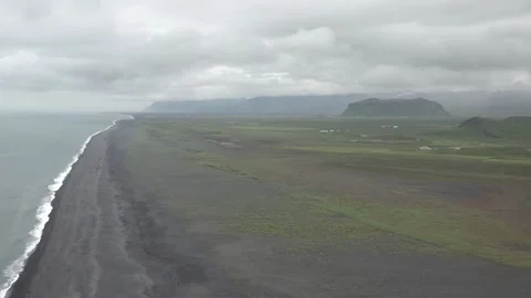 Waves rolling in over black sandy beach on a cloudy day Stock Footage 136461983