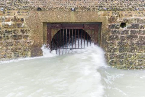 Waves rolling over the iron gates of pier structure Stock Photos