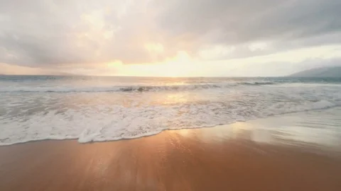 Waves rolling over the shore at sunset Stock Footage