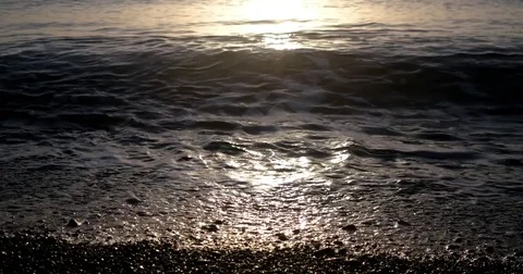 Waves Rolling in on a Pebble Coast Line at Sunrise With Glistening and Stock Footage 71795226